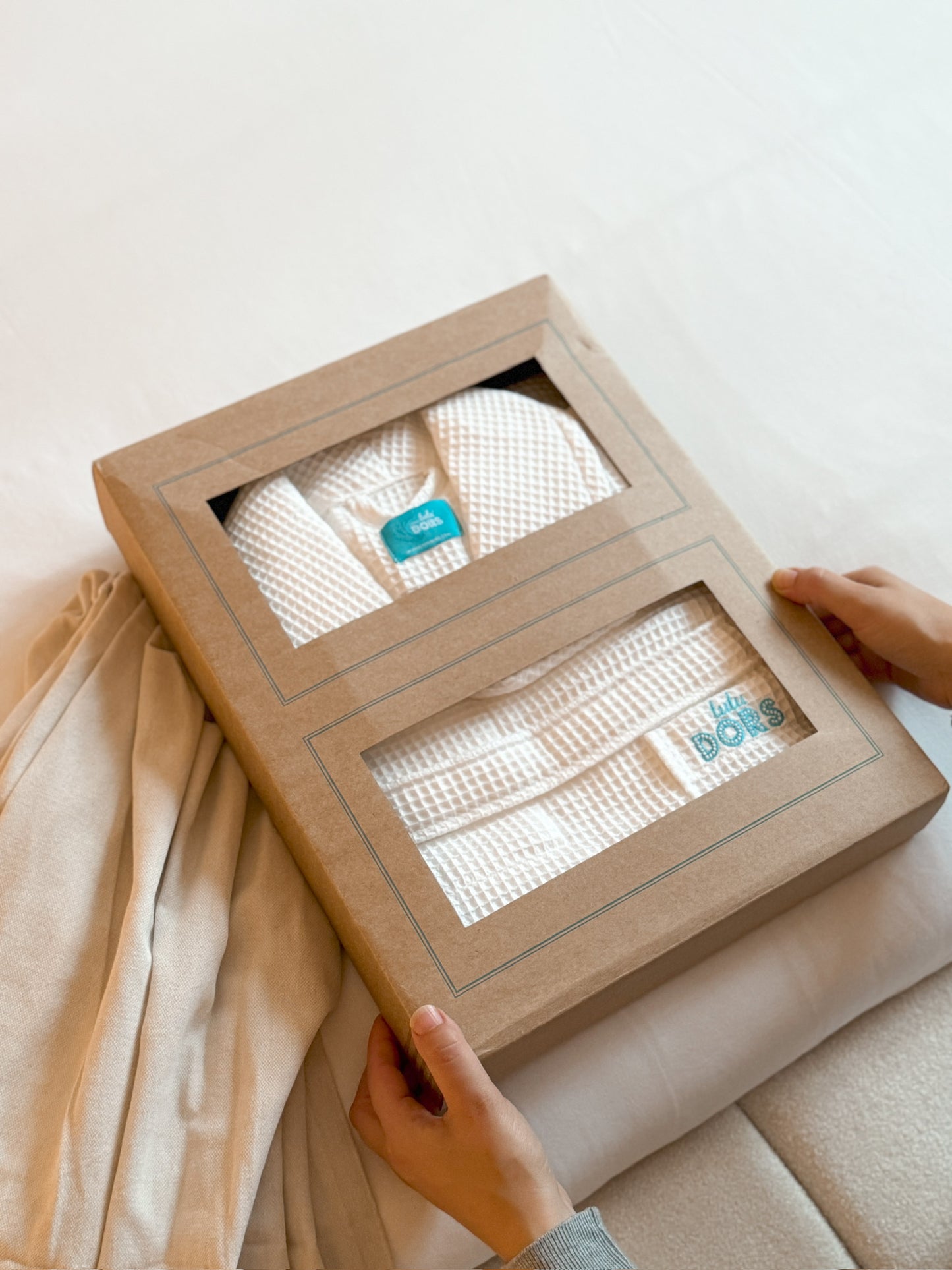 a Folded white waffle bathrobe with the brand name 'TUTU DORS' embroidered on the pocket in a nice gift box