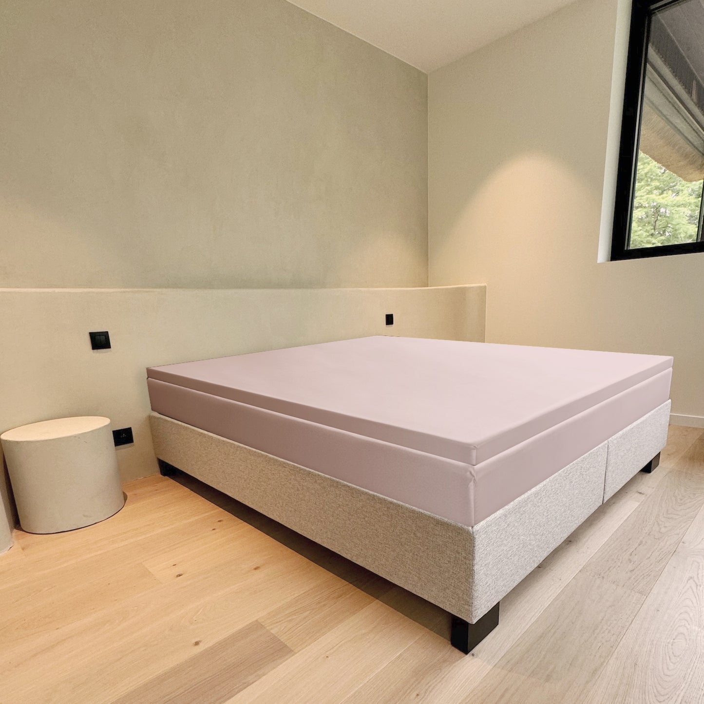 Bed with a mattress on a wooden floor in a room with a window.