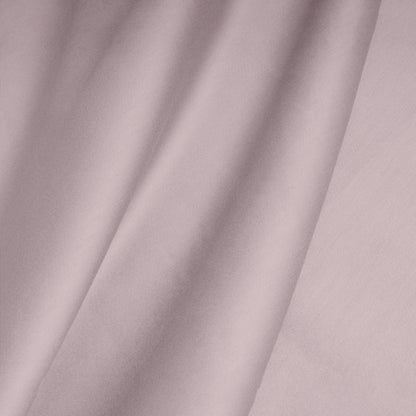 Close-up of a smooth, pink cotton satin fabric with folds.